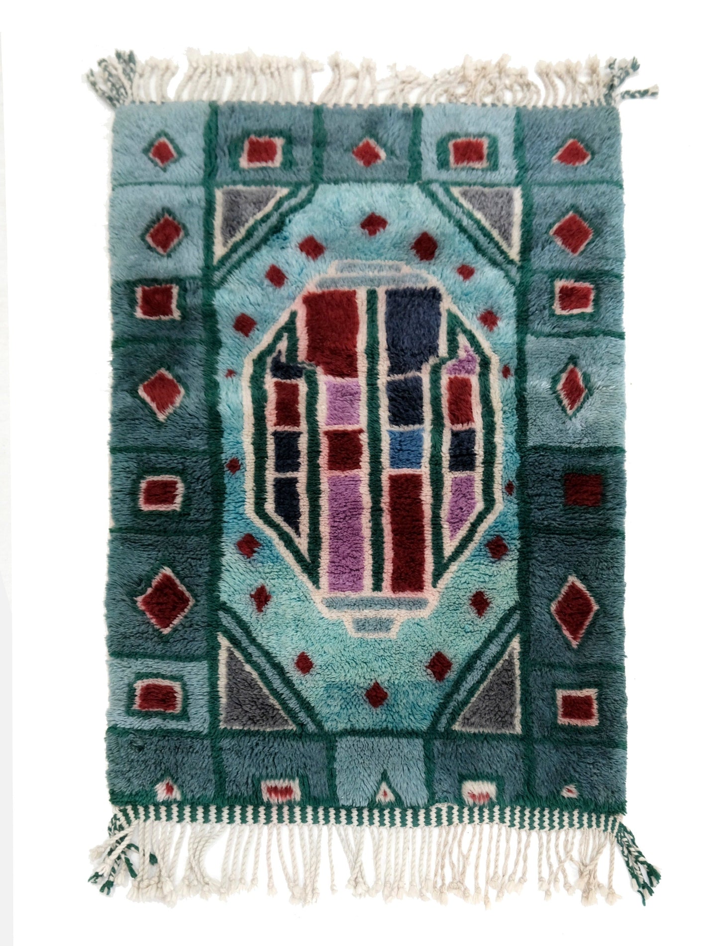 Handwoven plush wool Moroccan rug featuring a teal blue border and a central stained-glass style geometric medallion in burgundy, navy, and lavender, with a chunky cream fringe on a white background