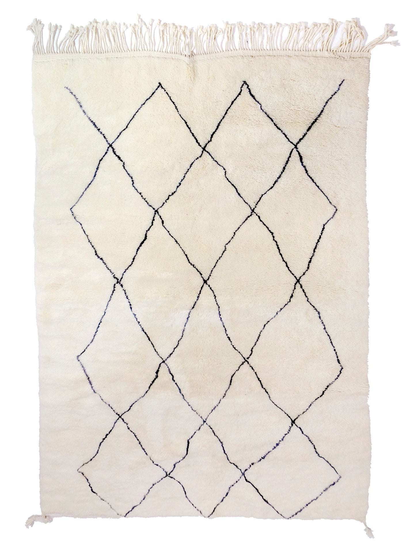 Plush cream wool Moroccan Beni Ourain rug with an irregular, hand-drawn black diamond lattice pattern, featuring a twisted top fringe and small braided corner ties, displayed on a white background.
