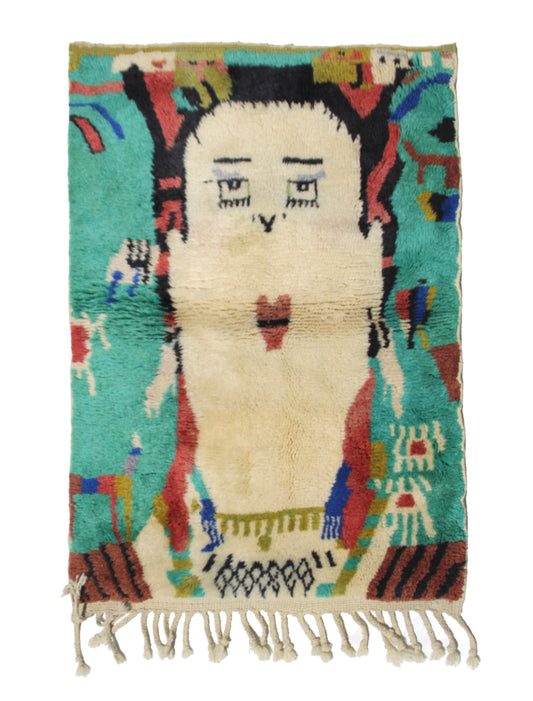 Hand-knotted Moroccan rug featuring a stylized abstract portrait face. Cream wool figure against a teal and turquoise background, with accents of black, rust red, and blue. Perfect for wall art or a bohemian nursery.


