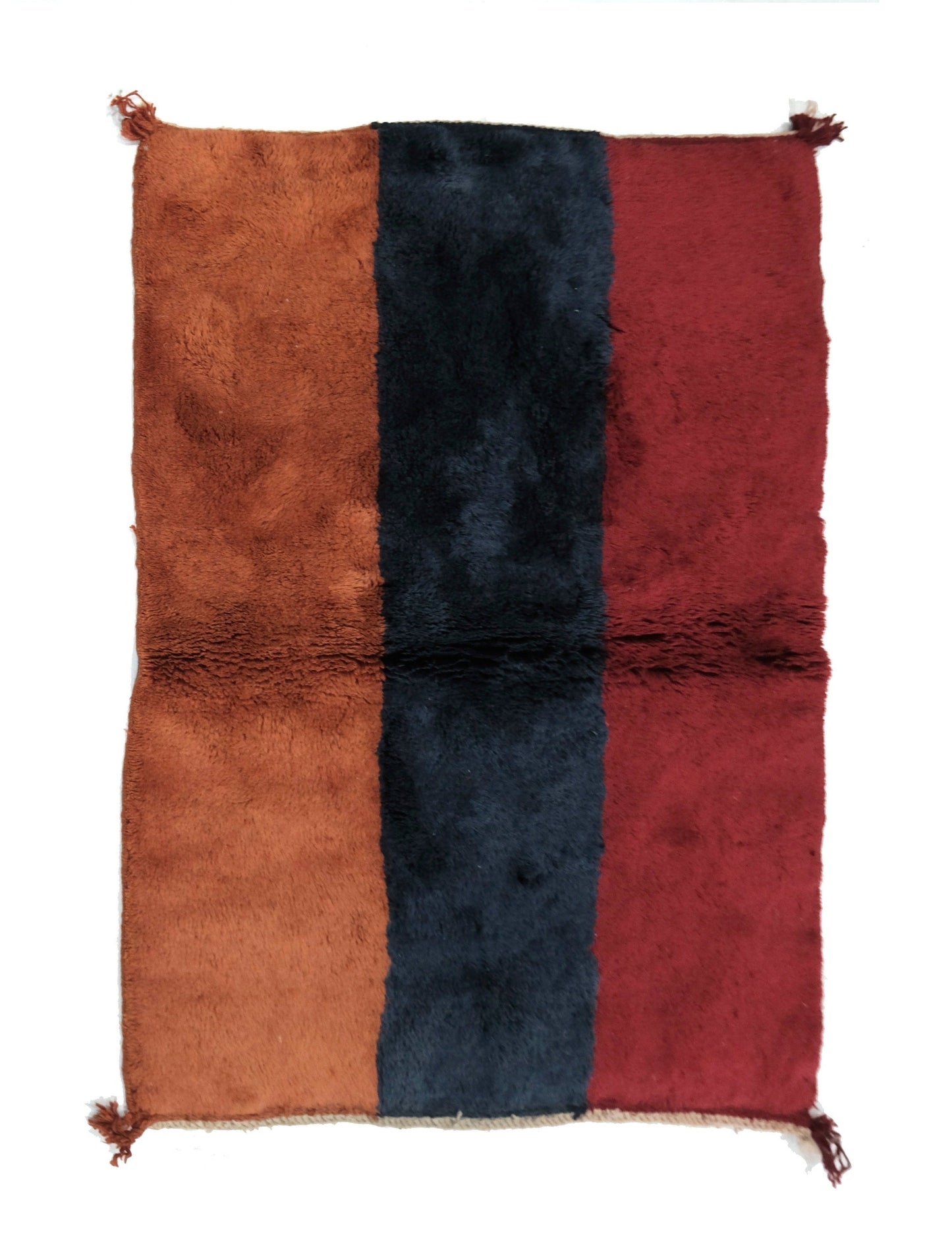 Plush hand-loomed wool rug featuring three wide vertical stripes in terracotta rust, navy blue, and deep burgundy red, with a horizontal central joining seam and small corner tassels, displayed on a white background