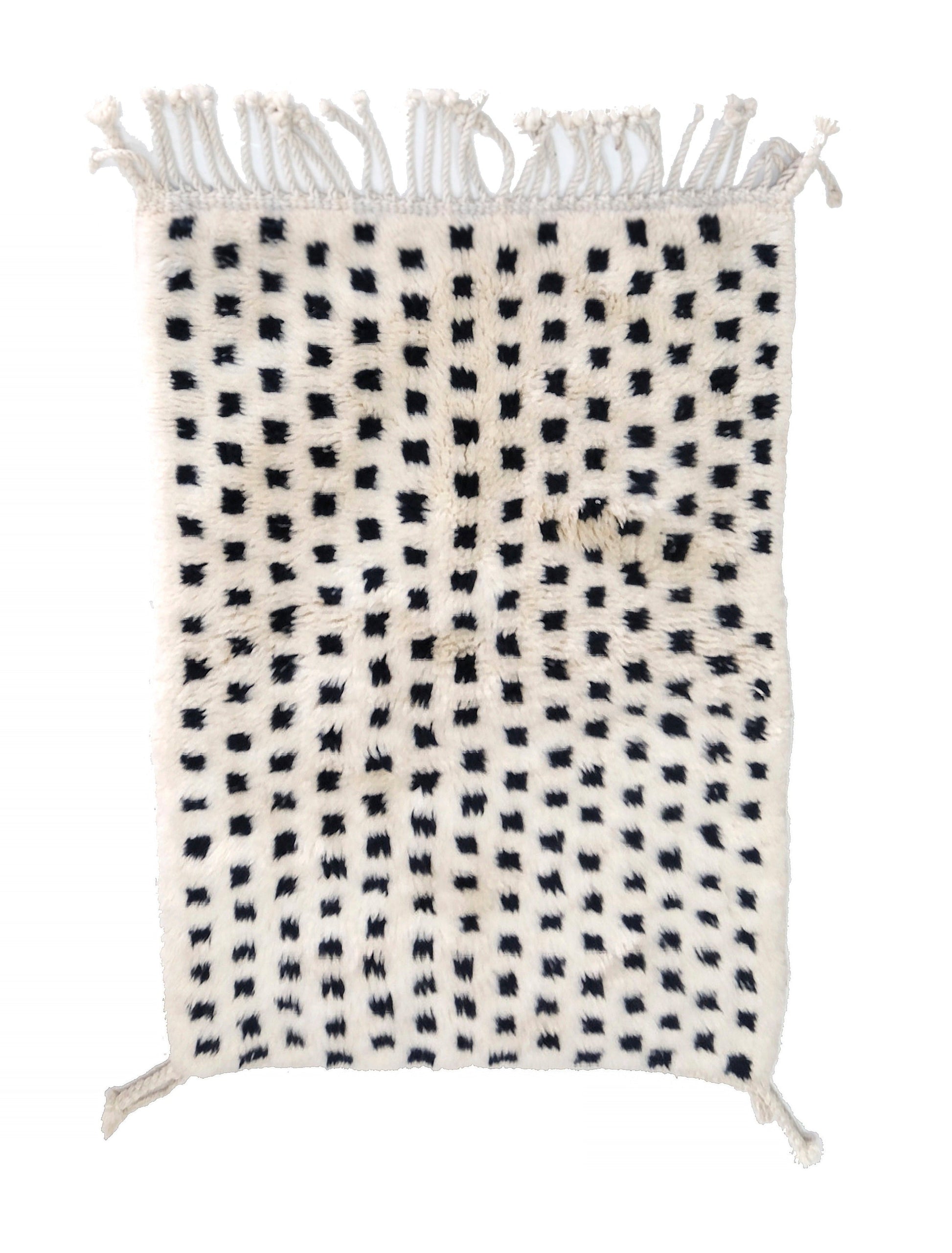 Plush cream wool rug with a grid of raised, fuzzy black tufted dots, featuring a chunky twisted top fringe and small braided corner ties, displayed on a white background.

