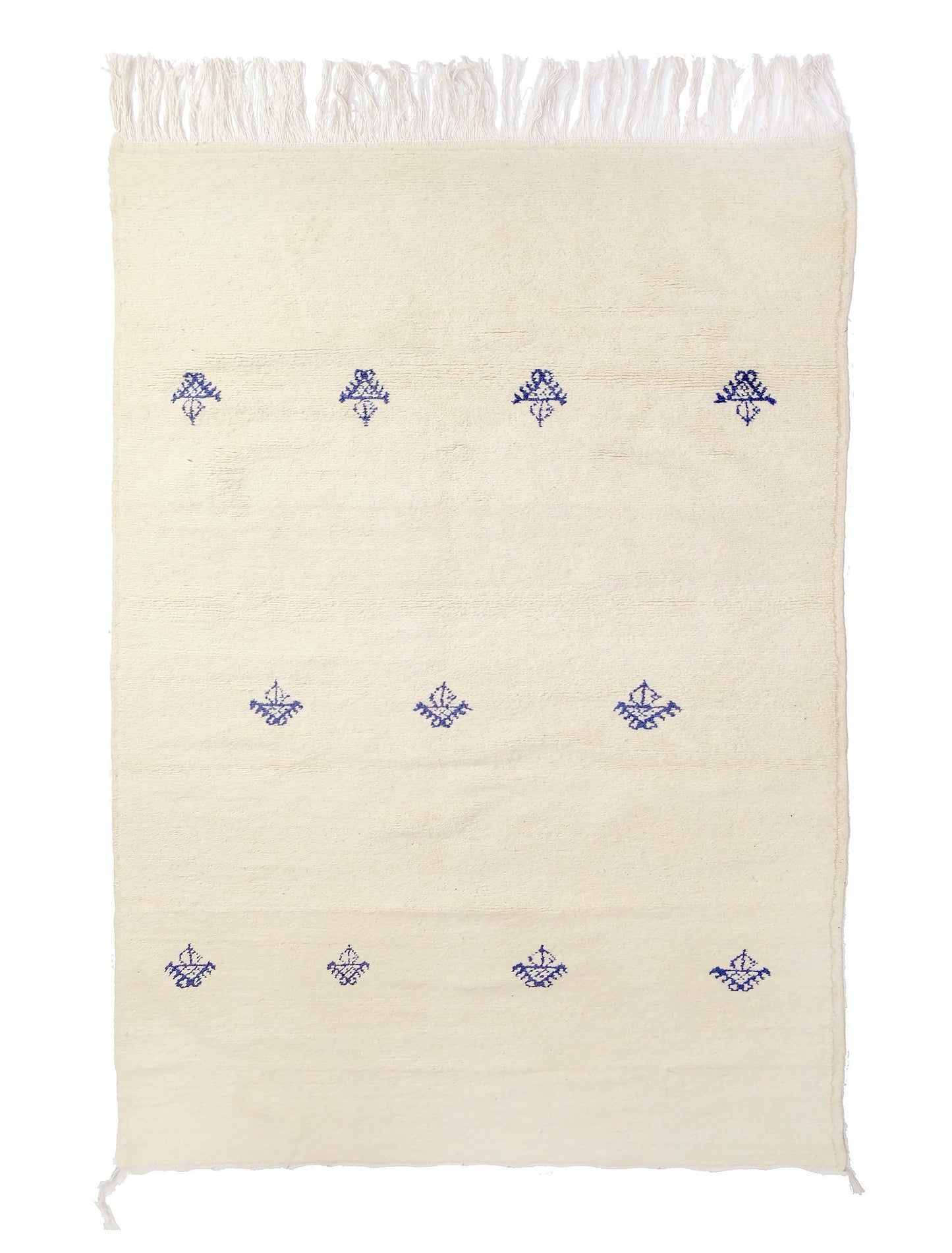 Soft cream hand-knotted wool rug featuring three sparse horizontal rows of deep indigo Berber tribal symbols, with knotted fringe on the top and bottom and small corner ties, displayed on a white background.