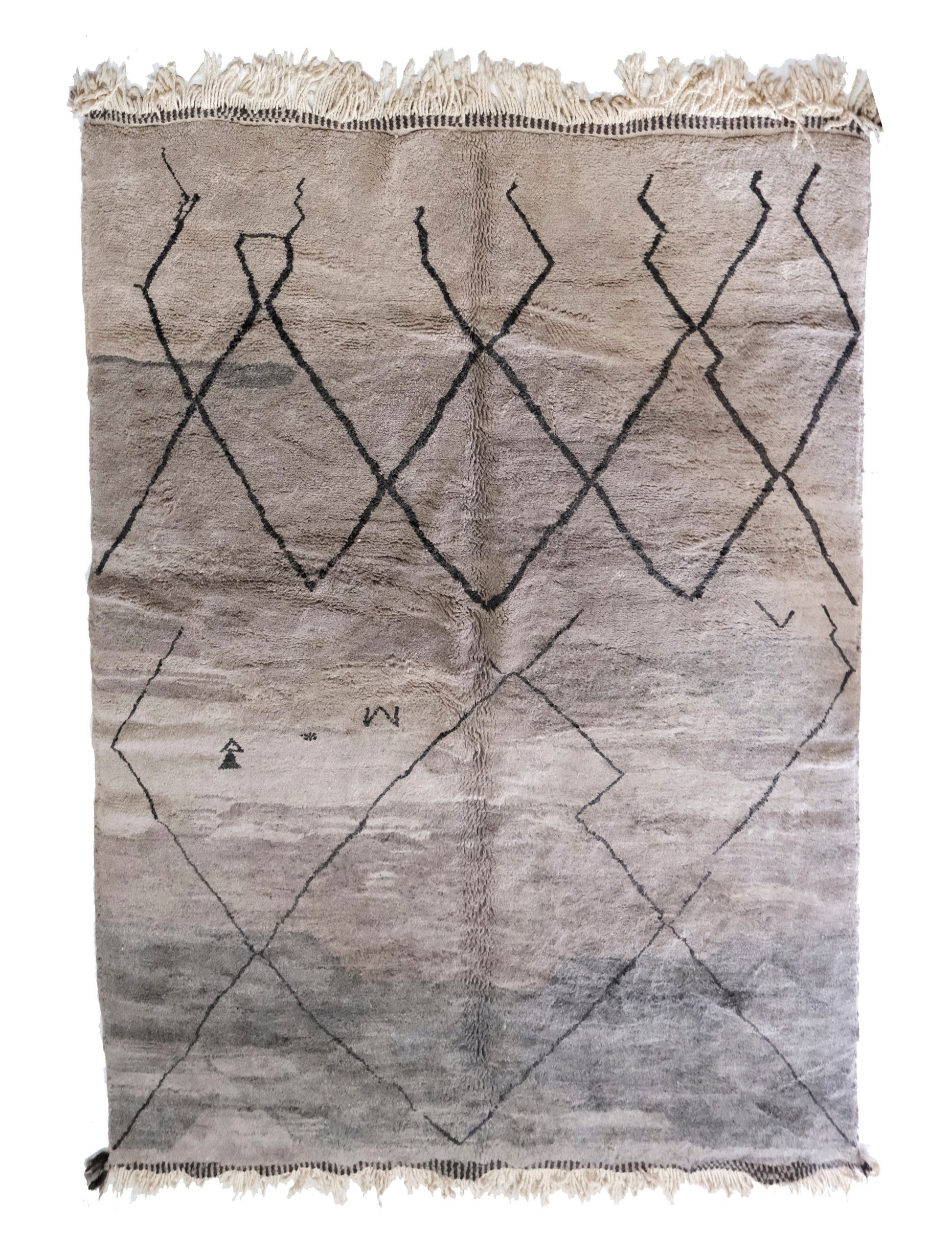 Muted grey plush handwoven Moroccan wool rug featuring a dark central joining seam, a "stepped" or broken black diamond lattice pattern, small scattered tribal motifs in the lower area, and cream fringe at the top and bottom, displayed on a white background.