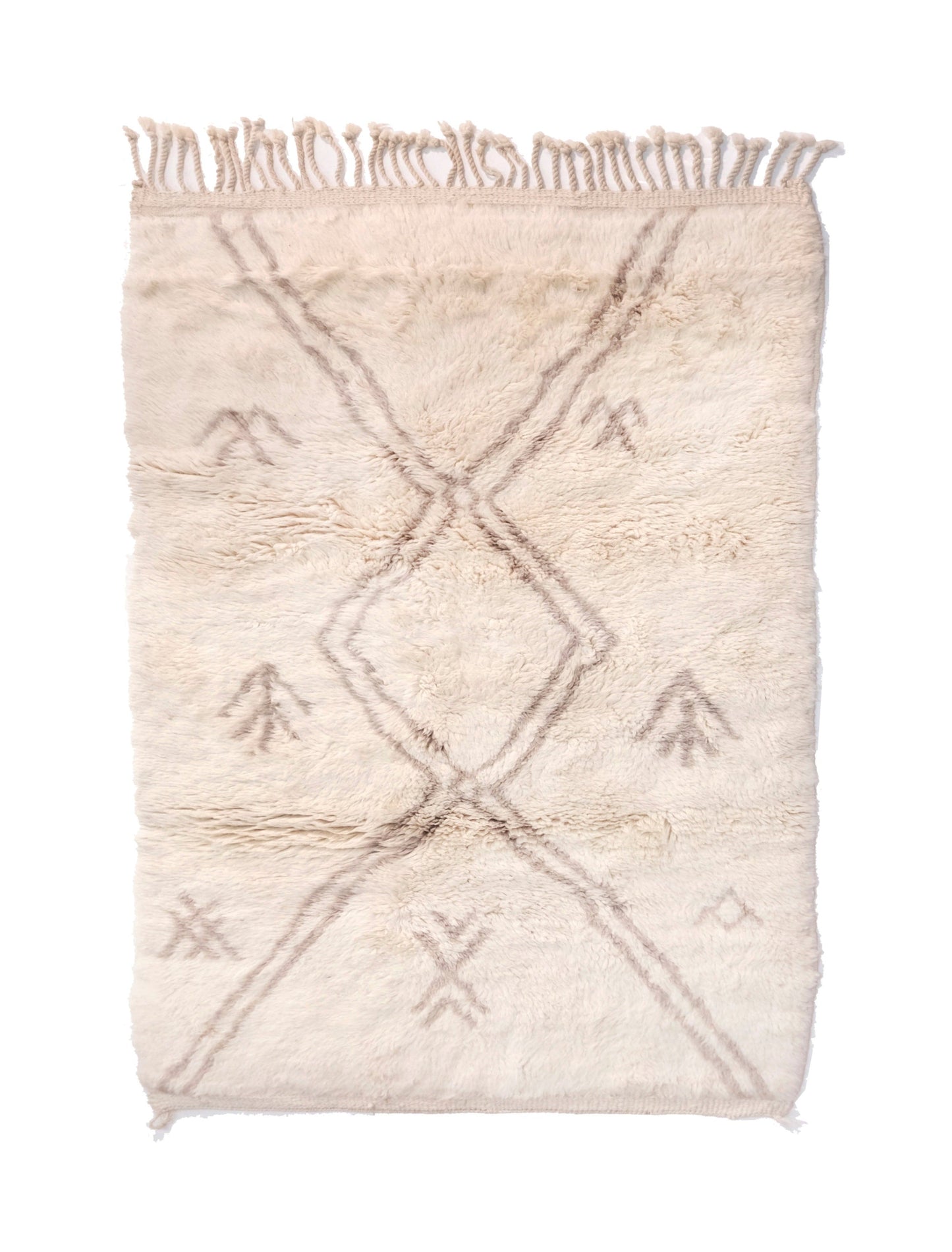 Plush cream wool Moroccan rug featuring a faded taupe geometric diamond lattice and scattered primitive tribal symbols, with a chunky top fringe and small braided bottom corner ties, displayed on a white background.

