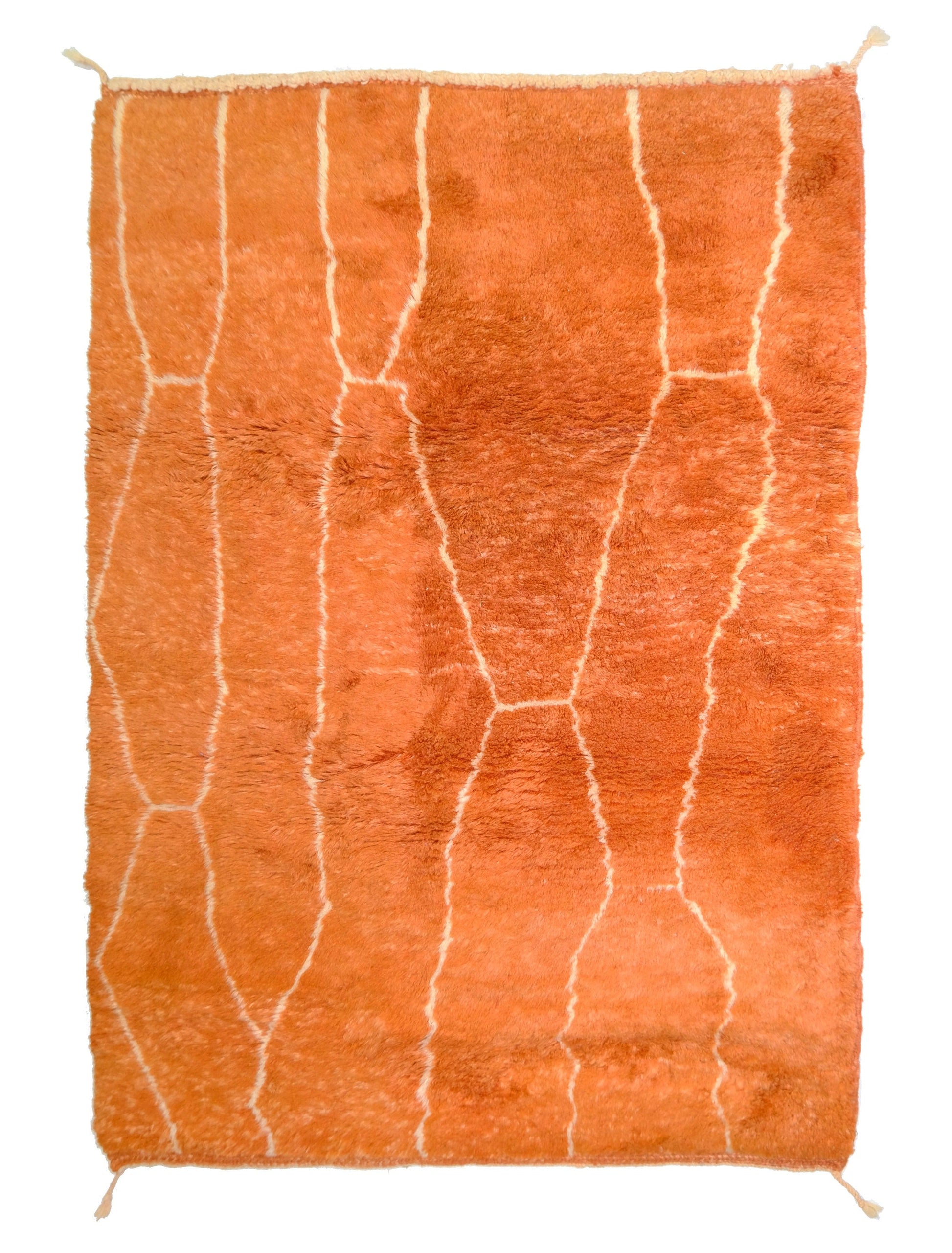 Plush burnt orange high-pile wool rug with a cream organic lattice pattern, top fringe, and small corner ties, displayed on a white background.